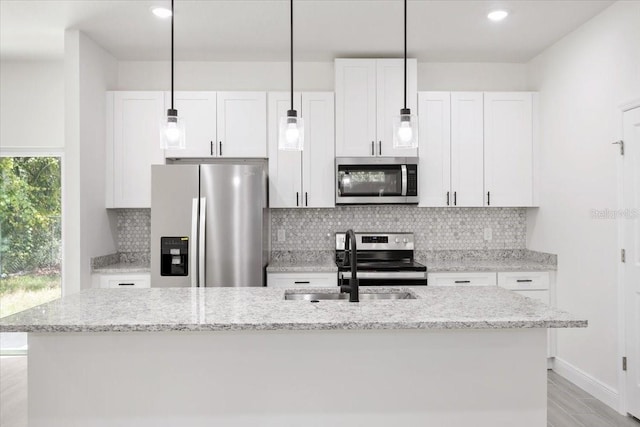 kitchen featuring light stone countertops, white cabinetry, an island with sink, and appliances with stainless steel finishes