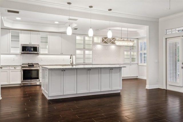 kitchen featuring pendant lighting, a kitchen island with sink, sink, appliances with stainless steel finishes, and white cabinetry