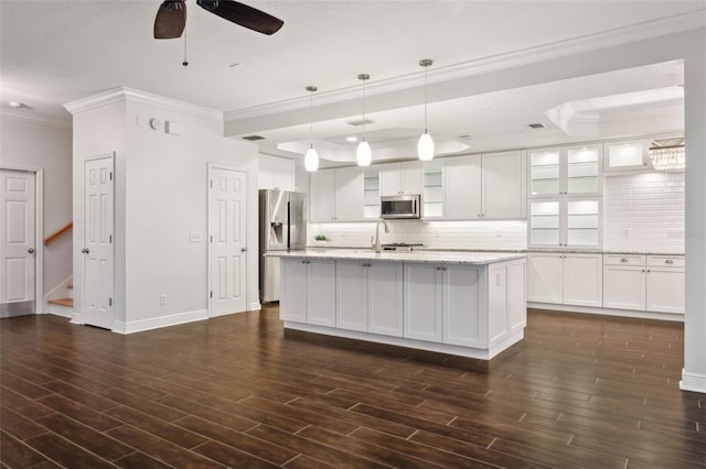 kitchen featuring appliances with stainless steel finishes, a kitchen island with sink, ceiling fan, white cabinets, and hanging light fixtures