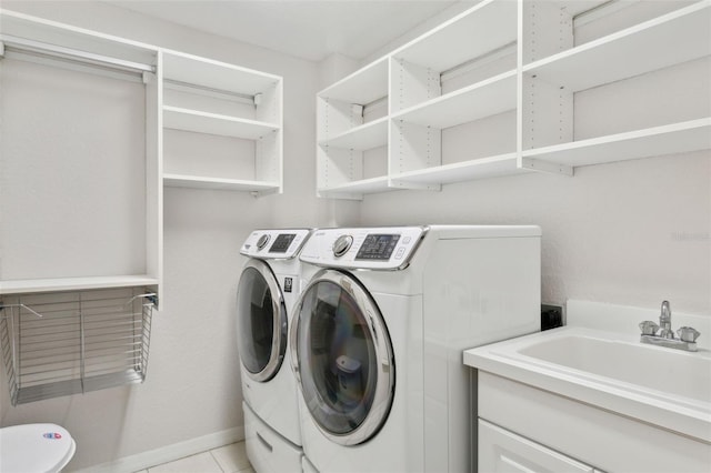 laundry room featuring light tile patterned floors, separate washer and dryer, and sink