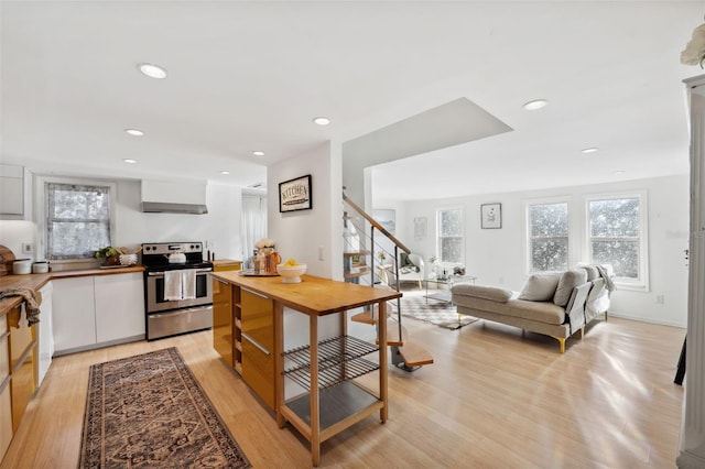 kitchen featuring wall chimney exhaust hood, electric range, light hardwood / wood-style flooring, and white cabinets