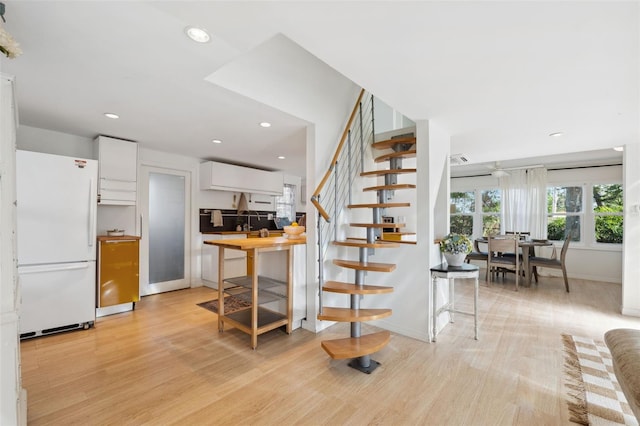 interior space with light hardwood / wood-style floors, decorative backsplash, white fridge, and white cabinetry