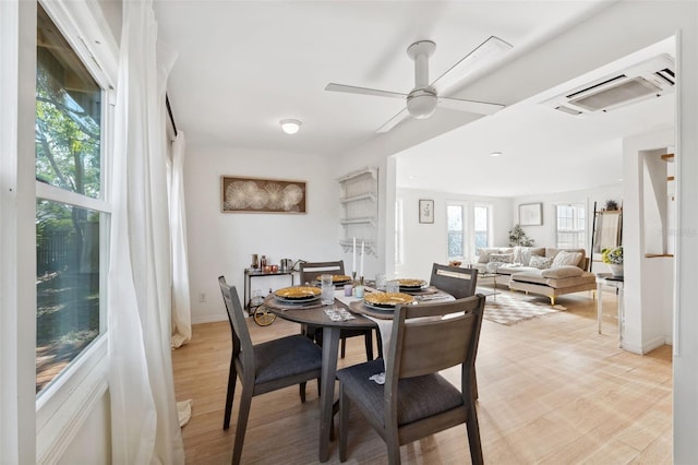 dining area with a wall mounted air conditioner, ceiling fan, and light wood-type flooring