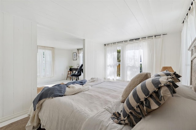 carpeted bedroom featuring wooden walls and wood ceiling