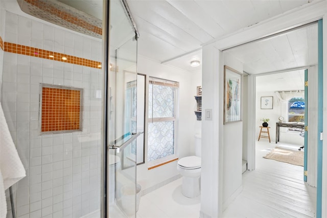 bathroom featuring tile patterned flooring, toilet, and a shower with door