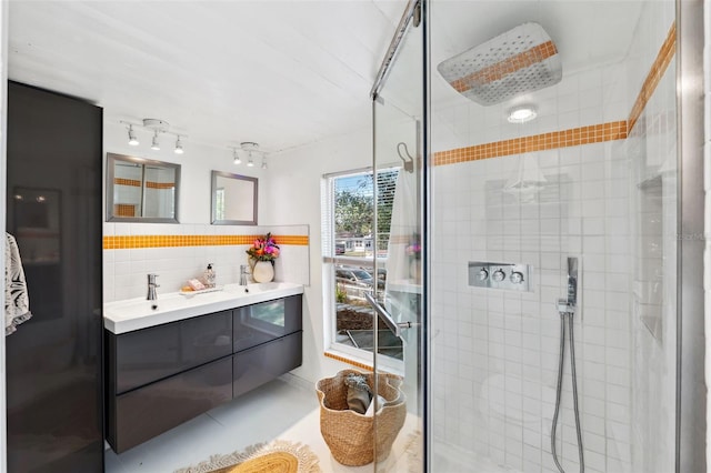 bathroom featuring vanity, a shower with shower door, and tasteful backsplash