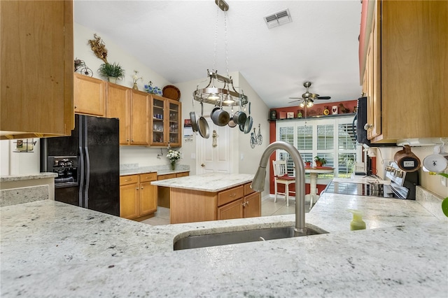 kitchen with lofted ceiling, black appliances, sink, ceiling fan, and a kitchen island