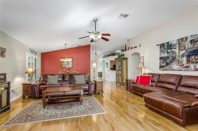 living room with ceiling fan with notable chandelier, light wood-type flooring, and lofted ceiling