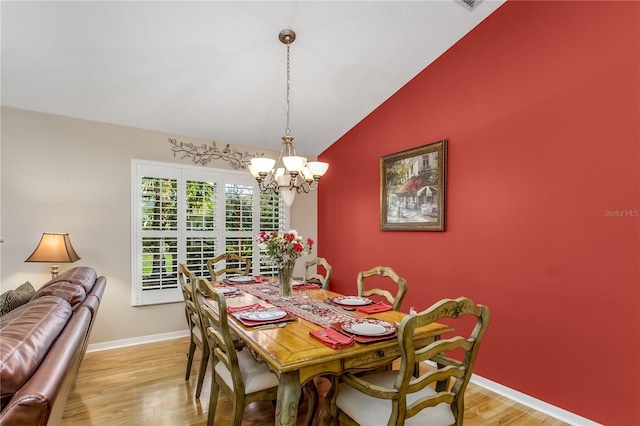 dining space featuring light wood-type flooring, lofted ceiling, and a notable chandelier