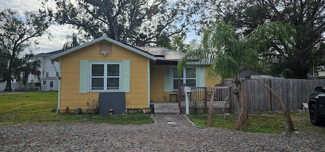 bungalow featuring solar panels and a front lawn