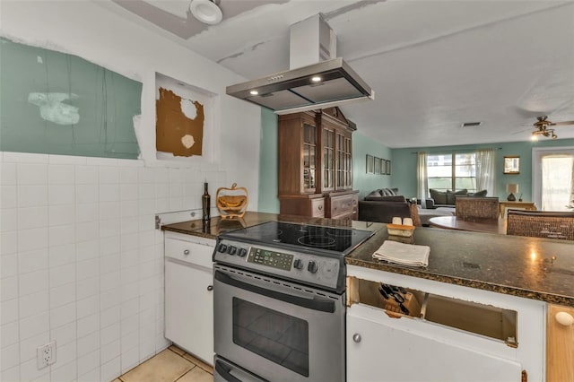 kitchen with stainless steel electric stove, ceiling fan, light tile patterned floors, white cabinetry, and island exhaust hood