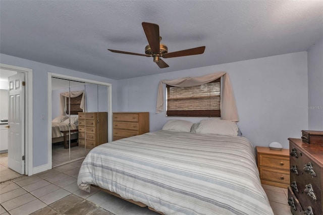 tiled bedroom featuring ceiling fan, a textured ceiling, and a closet