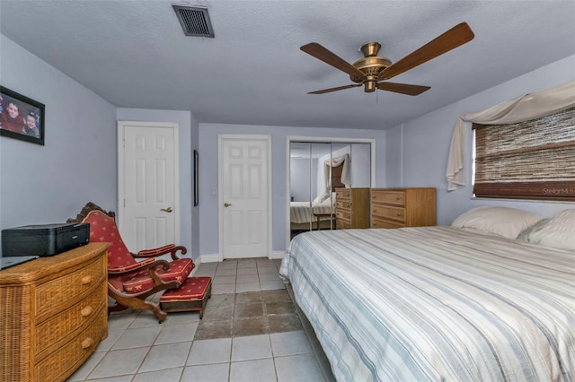 tiled bedroom with a textured ceiling, a closet, and ceiling fan