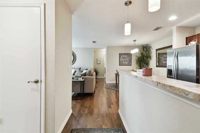 kitchen with dark hardwood / wood-style floors, stainless steel fridge with ice dispenser, a textured ceiling, and decorative light fixtures