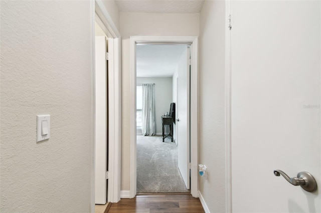 hall with a textured ceiling and dark hardwood / wood-style floors