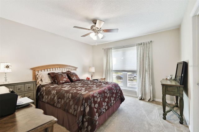 bedroom featuring a textured ceiling, light colored carpet, and ceiling fan