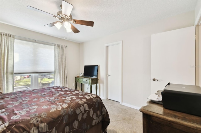 bedroom featuring ceiling fan, light carpet, and a textured ceiling