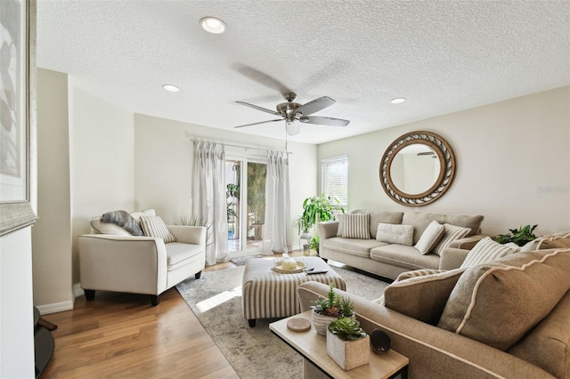 living room with hardwood / wood-style floors, a textured ceiling, and ceiling fan