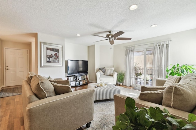 living room featuring wood-type flooring, a textured ceiling, and ceiling fan