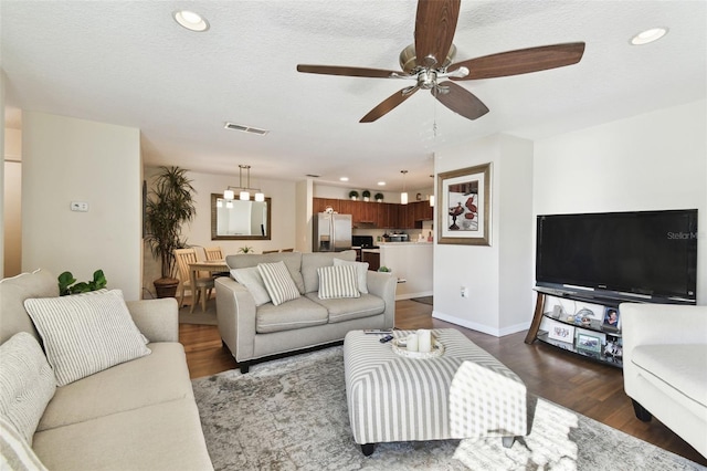 living room with ceiling fan with notable chandelier and dark wood-type flooring