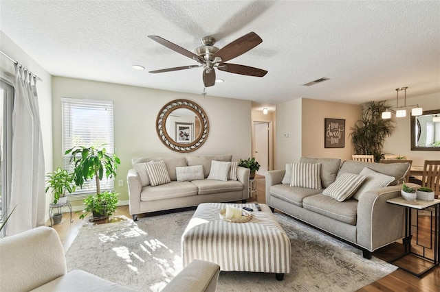 living room with ceiling fan, a textured ceiling, and hardwood / wood-style flooring