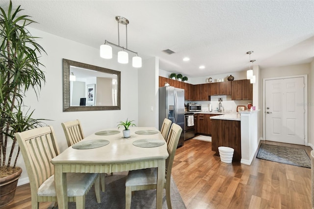 dining space featuring a textured ceiling, dark hardwood / wood-style floors, and sink