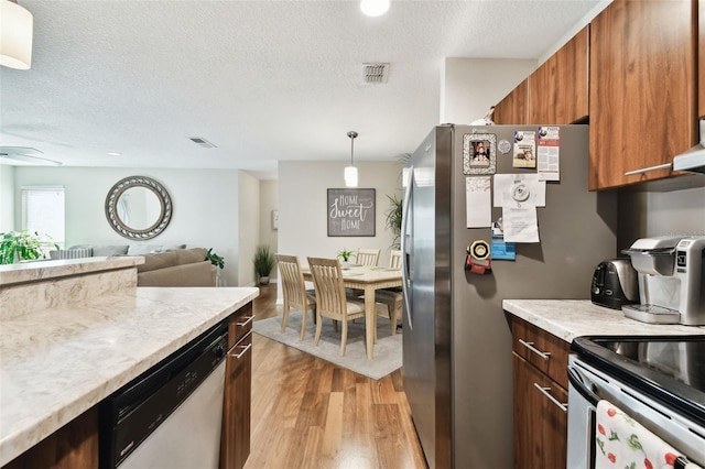 kitchen featuring pendant lighting, light hardwood / wood-style floors, stainless steel appliances, and a textured ceiling