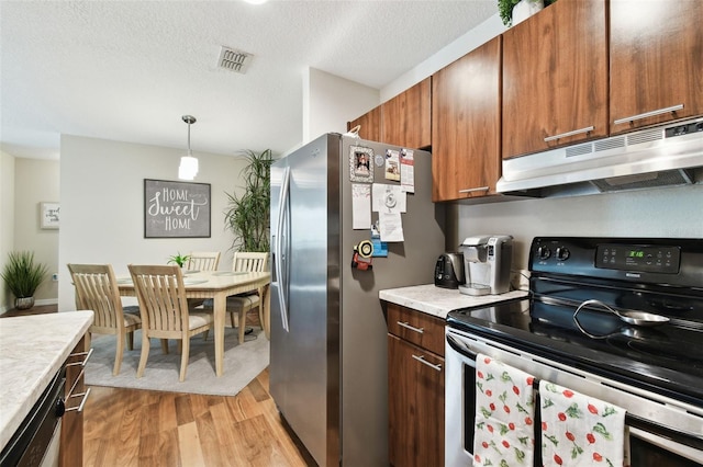 kitchen with appliances with stainless steel finishes, a textured ceiling, decorative light fixtures, and light hardwood / wood-style floors