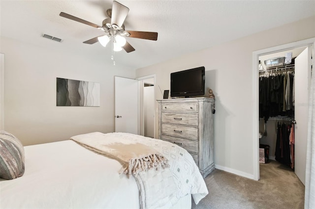 carpeted bedroom with ceiling fan, a spacious closet, and a closet