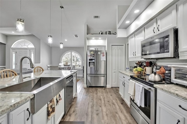 kitchen featuring white cabinetry, sink, light stone countertops, hanging light fixtures, and stainless steel appliances