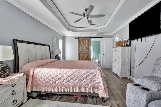 bedroom featuring a raised ceiling, ceiling fan, crown molding, a barn door, and hardwood / wood-style flooring