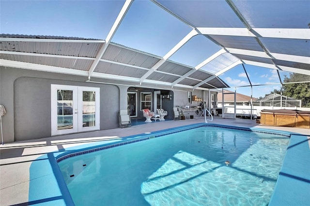 view of pool with glass enclosure, a hot tub, and a patio area