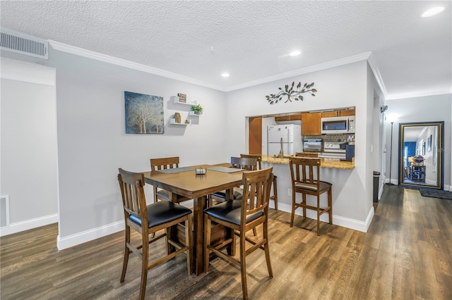 dining space featuring dark hardwood / wood-style flooring, ornamental molding, and a textured ceiling