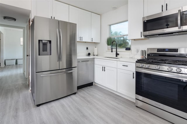 kitchen with light hardwood / wood-style floors, white cabinetry, sink, and appliances with stainless steel finishes