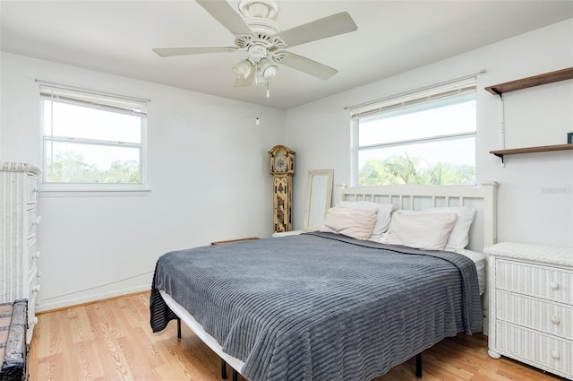 bedroom featuring ceiling fan, light hardwood / wood-style floors, and multiple windows