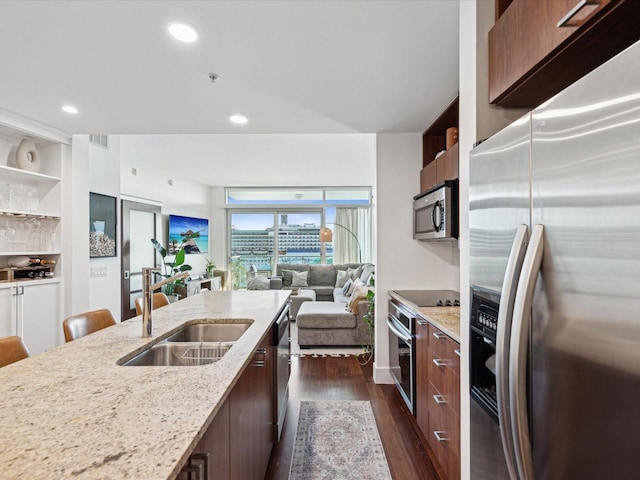 kitchen with light stone countertops, dark hardwood / wood-style floors, appliances with stainless steel finishes, built in features, and sink