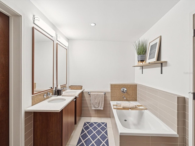 bathroom with a relaxing tiled tub, tile patterned flooring, and vanity