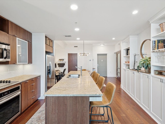 kitchen featuring a breakfast bar, a kitchen island with sink, dark hardwood / wood-style flooring, appliances with stainless steel finishes, and sink