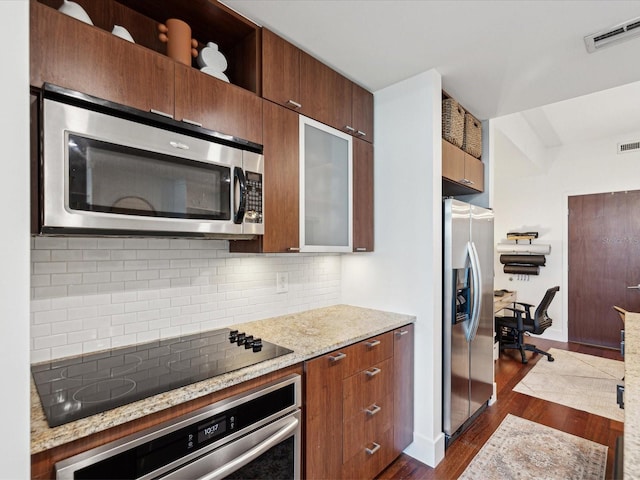 kitchen featuring light stone counters, stainless steel appliances, backsplash, and dark wood-type flooring