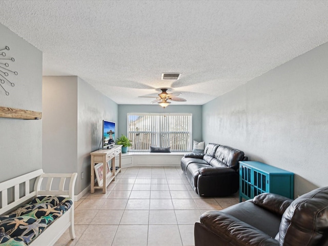 living room with ceiling fan, a textured ceiling, and light tile patterned flooring