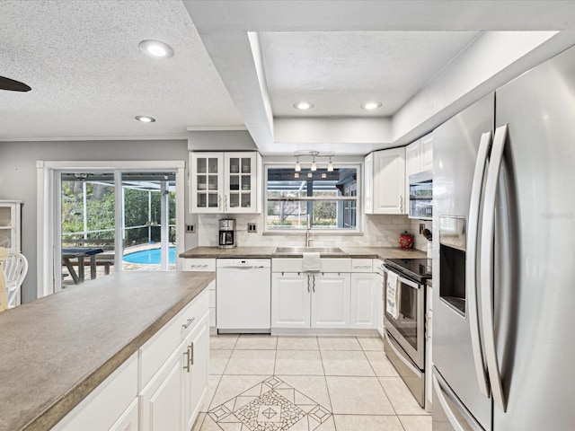 kitchen featuring appliances with stainless steel finishes, sink, backsplash, white cabinetry, and light tile patterned flooring