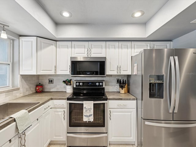 kitchen with white cabinets, appliances with stainless steel finishes, and tasteful backsplash