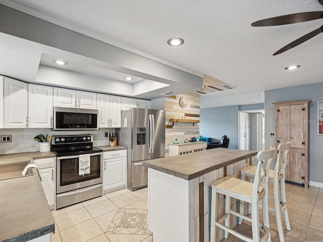 kitchen featuring a center island, white cabinetry, stainless steel appliances, light tile patterned flooring, and a breakfast bar