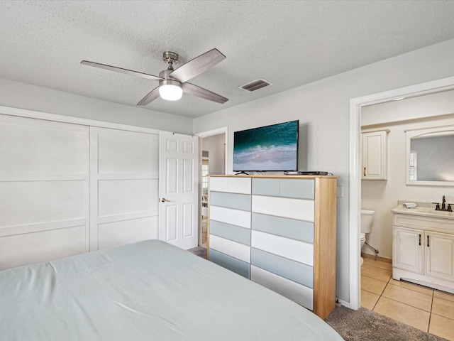 tiled bedroom featuring a closet, ceiling fan, a textured ceiling, and sink