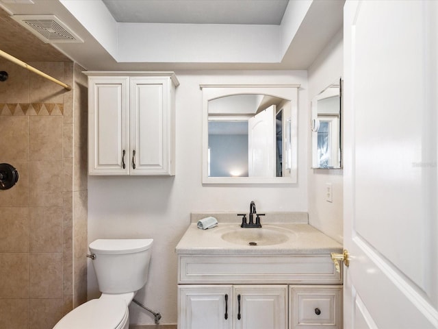 bathroom with toilet, vanity, and a tile shower