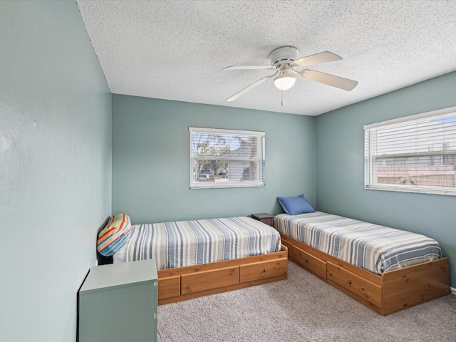 bedroom featuring ceiling fan, a textured ceiling, carpet floors, and multiple windows