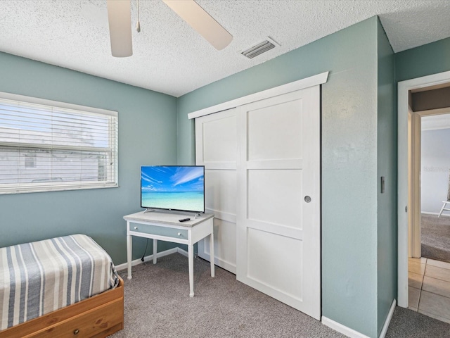 carpeted bedroom featuring a textured ceiling and ceiling fan