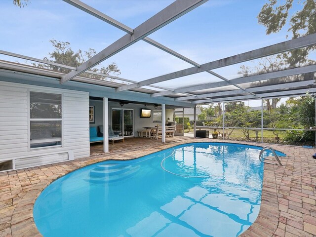 view of swimming pool with ceiling fan, a patio area, and a lanai