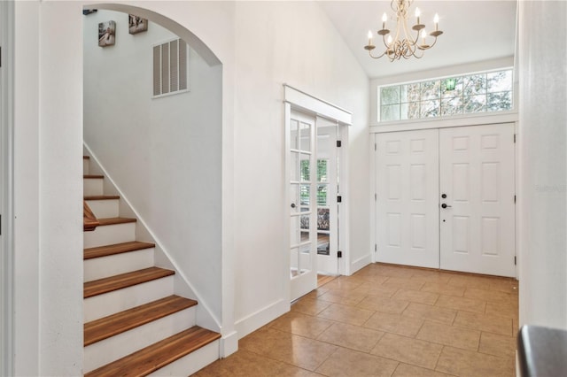 foyer featuring light tile patterned floors, vaulted ceiling, and a notable chandelier