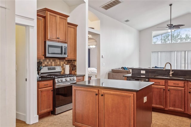 kitchen featuring stainless steel appliances, ceiling fan, sink, a center island, and lofted ceiling